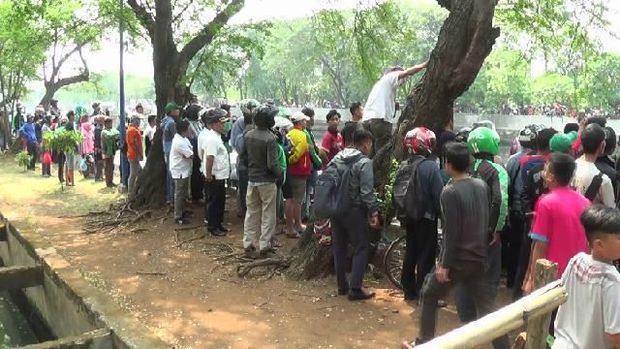 Warga  menonton pria diduga jambret yang nyebur ke kali