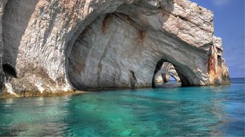 Gua Zakynthos di Yunani dapat dikunjungi dengan menggunakan sampan. Di alamnya, tembok berwarna putih yang memantulkan warna air memberikan gua ini nuansa biru yang kental. Foto: Matador Network