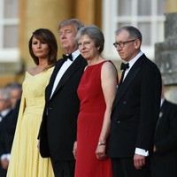 Theresa May pun menganggap serius dresscode di hari itu. Ia tampil anggun berbalut gaun sleeveless merah, sementara suaminya memakai tuksedo klasik seperti Donald Trump. Foto: Getty Images
