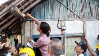 Rini sempat memasang bola lampu di salah satu rumah warga. Pool/Kementerian BUMN.