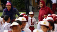 Seorang guru mengantarkan salah seorang murid yang datang terlambat di hari pertama masuk sekolah ini.