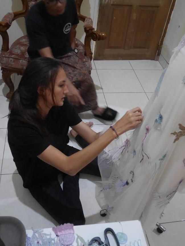 Diungkapkan sang desainer, Surya Abduh, Nadine dan Dimas sangat terlibat dalam proses pembuatan gaun tersebut. Bahkan, Puteri Indonesia 2005 itu ikut menjahit detail ubur-ubur yang menghiasi gaun putihnya. Seperti yang terlihat pada foto ini. (Foto: Dok. Surya Abduh)