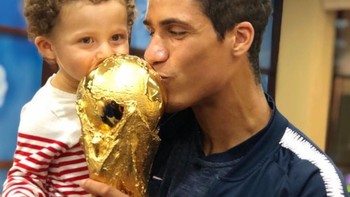 Raphael Varane mengajak anaknya ikut mencium piala tersebut. Foto: istimewa