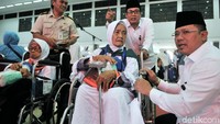 Petugas membantu jemaah yang memakai kursi roda.