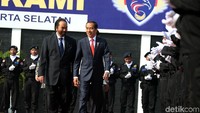 Jokowi datang mengenakan setelan jas warna biru tua dan dasi merah.