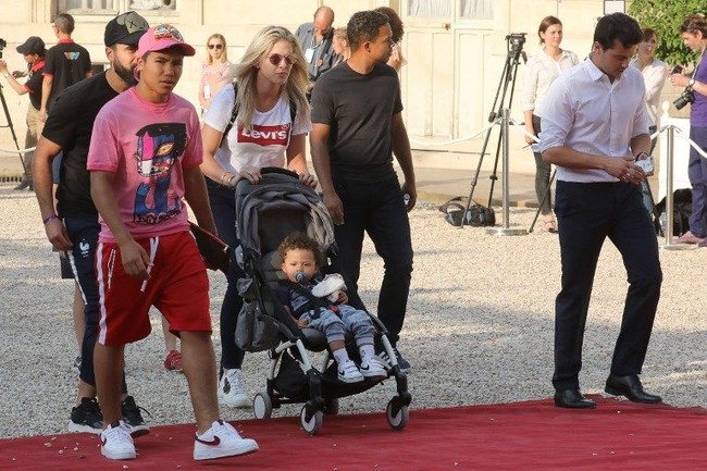 Gaya casual jadi pilihan Camile Tygat istri pemain belakang Prancis, Raphael Varane. Tygat yang merupakan mahasiswi sekolah hukum ini terlihat mengenakan kaus Levi’s, celana jeans dan sneakers. Dia terlihat mendorong stroller sang anak, Ruben. Foto: AFP