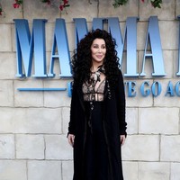 Pada kesempatan itu, Cher mengandalkan busana serba hitam dengan bralet transparan yang mempertegas keseskiannya. Namun coat hitam menjaga penampilannya agar tak terasa berlebihan. (Foto: Getty Images)