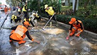 Pasukan Oranye dan pemadam kebakaran bahu-membahu membersihkan trotoar di kawasan Monas, Jakarta.