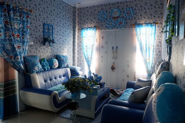 Ruang tamu dengan sofa biru-putih ini dihiasi wallpaper bergambar kepala Doraemon. Ada pula hiasan bunga berwarna senada, tak ketinggalan tirai dan hiasan dinding serta bantal sofa Doraemon. Foto: Instagram/@reghinakarwur