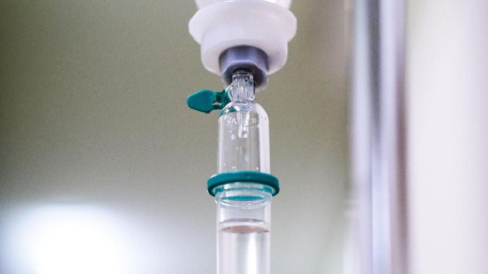 Intravenous therapy iv infusion set and bottle on a pole. Liquid saline is slowly dripping drops of drugs, medicine or antibiotic therapy and surgery recovery in a hospital or clinic.