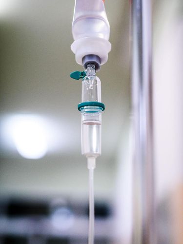 Intravenous therapy iv infusion set and bottle on a pole. Liquid saline is slowly dripping drops of drugs, medicine or antibiotic therapy and surgery recovery in a hospital or clinic.