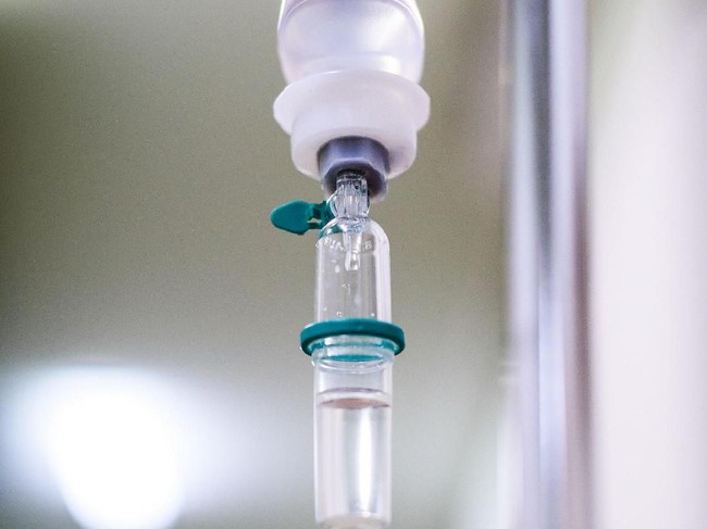 Intravenous therapy iv infusion set and bottle on a pole. Liquid saline is slowly dripping drops of drugs, medicine or antibiotic therapy and surgery recovery in a hospital or clinic.