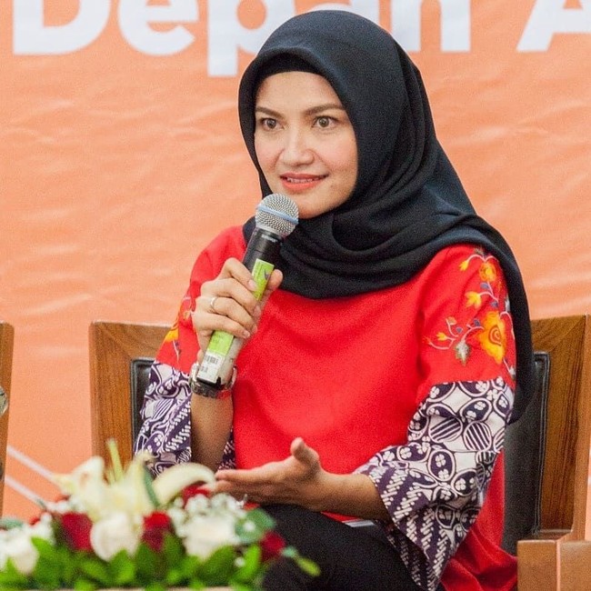 Seperti saat Tina menjadi pembicara bersama Kepala Bappenas tentang pencegahan stunting. Tina tampil formal dengan atasan motif batik berwarna merah dipadukan dengan hijab segi empat berwarna hitam. Foto: Instagram Tina Talisa