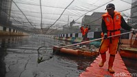 Petugas memunguti sampah yang mengapung di sungai.