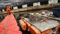 Petugas Dinas Lingkungan Hidup DKI Jakarta menyusuri sungai untuk menyelesaikan tugasnya.