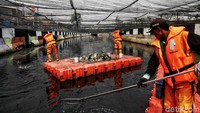 Petugas Dinas Lingkungan Hidup DKI Jakarta menyusuri sungai untuk membersihkan sampah.