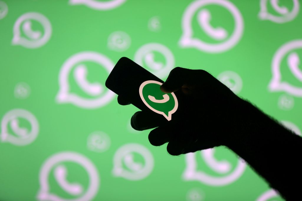 FILE PHOTO: A man poses with a smartphone in front of displayed Whatsapp logo in this illustration September 14, 2017. REUTERS/Dado Ruvic/File Photo