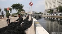 Pekerja menyiapkan waring yang akan dipasang di atas kali.