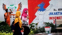 Warga melintas diantara mural-mural di kawasan Lapangan Tembak.