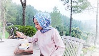 Di sebuah kafe berkonsep outdoor, Poppy duduk santai sambil menikmati segelas kopi. Ia juga ditemani sepiring camilan.  Foto: Instagram @poppybungariphat