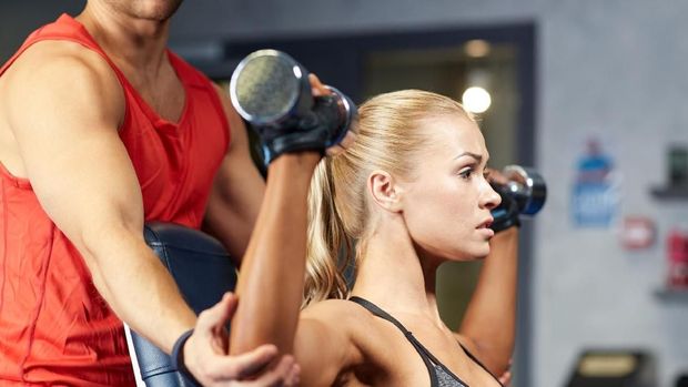 Ilustrasi seorang instruktur melakukan spotting atau membantu klien melakukan angkat beban.