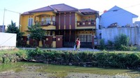 Rumah tersebut berdiri dalam satu cluster perumahan yang jumlahnya kurang dari 10 unit rumah. Di sebelah kirinya terdapat kos-kosan.