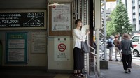 Seorang warga Jepang sedang memakai kipas untuk menyegarkan diri di tengah cuaca panas ekstrem. Foto: AFP PHOTO/Martin BUREAU