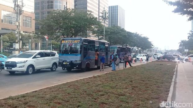 Warga menunggu bus di jalan raya.