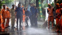 Petugas gabungan dari PPSU dan Damkar tengah melakukan pembersihan trotoar.