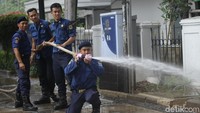 Petugas Damkar menyemprotkan air untuk membersihkan sisa busa di trotoar.