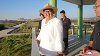 Mengenakan kemeja putih dipadu dengan topi fedora, Kim terlihat sangat percaya diri. Korean Central News Agency (KCNA) via REUTERS.