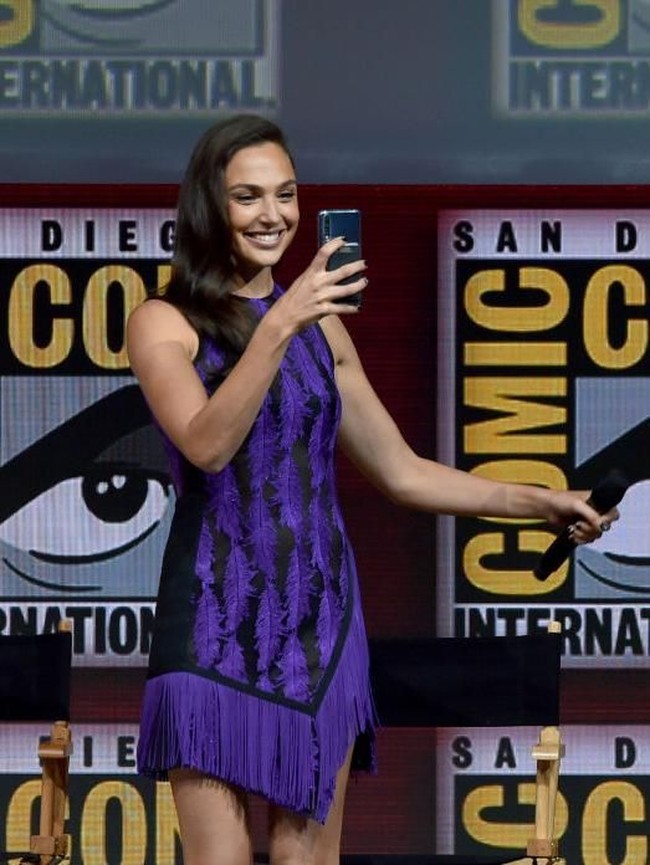 Tiba di atas panggung, Gal langsung menyapa para penggemar dan jurnalis yang telah menunggu para bintang Wonder Woman 1984. Ia lalu merekam momen tersebut dengan ponselnya. (Foto: Kevin Winter/Getty Images)