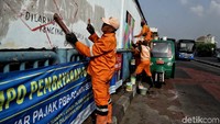 Beberapa petugas PPSU tampak membuat pola terlebih dahulu sebelum melakukan pengecatan.