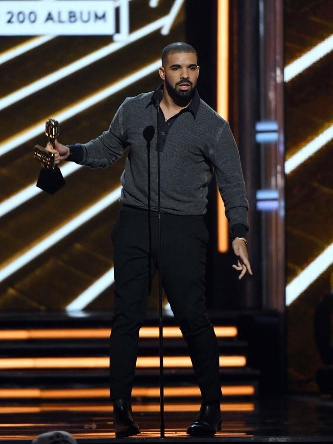 Berjaya di Billboard Music Awards 2017, Drake tampil modis dengan padanan polo shirt hitam, celana formal, dan sepatu oxford berwarna senada. (Foto: Getty Images)