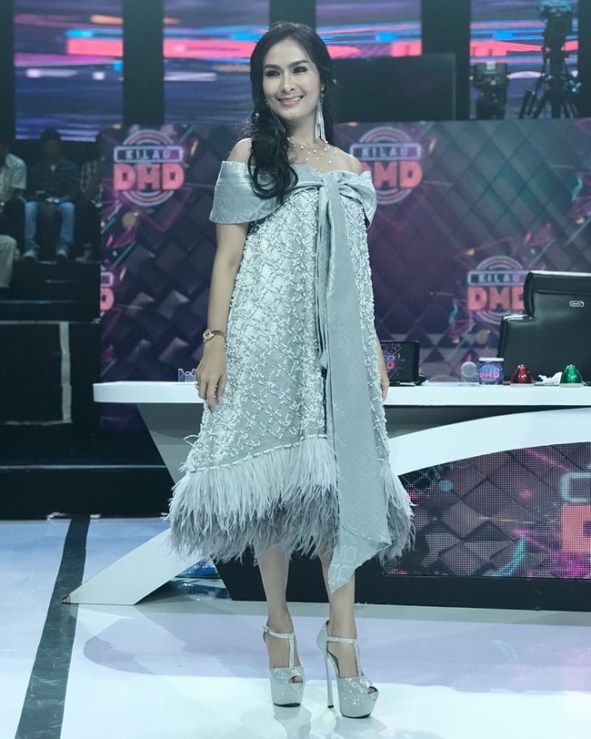 Iis Dahlia terlihat meriah dalam balutan gaun silver dengan detail pita besar. Gaun tampak semakin heboh dengan detail fringe di bagian bawahnya. Foto: Instagram @ isdadahlia
