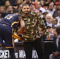 Pria 31 tahun ini juga tak mau melewatkan laga NBA hanya dengan tampil biasa-biasa saja. Hoodie bermotif kamuflase sukses mengangkat gaya Drake. (Foto: Getty Images)