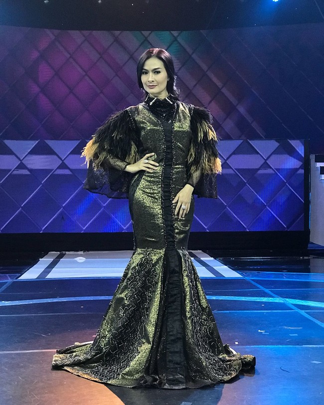 Iis Dahlia bergaya bling bling nan glamour dalam balutan gaun hitam keemasan yang dihiasi bulu di bagian lengannya ini. Foto: Instagram @ isdadahlia