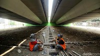 Dua orang pekerja beristirahat sejenak sambil memandangi flyover yang akan dicat.