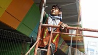 Seorang pekerja memanjat tangga untuk mengecat flyover.