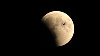 Momen munculnya gerhana bulan total diiringi dengan sebuah pesawat terbang yang tertangkap lensa kamera. Anadolu Agency/Getty Images.