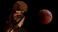 Bulan purnama terbit selama gerhana di belakang patung Dewi Athena kuno di Athena, Yunani, 27 Juli 2018. REUTERS / Costas Baltas