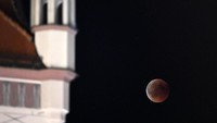Blood Moon terlihat selama gerhana bulan penuh di sebelah balai kota tua di Munich, Jerman, 27 Juli 2018. REUTERS / Andreas Gebert