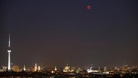 Bulan dan mars (kanan) terlihat selama gerhana bulan terlihat di atas lanskap kota dan menara televisi di Berlin, Jerman, 27 Juli 2018. REUTERS / Fabrizio Bensch