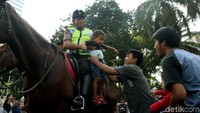 Seorang anak usai menunggang kuda bersama polisi.