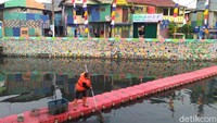 Tampak seorang petugas kebersihan sedang membersihkan aliran sungai (Foto: Yuni Ayu Amida/detikcom)
