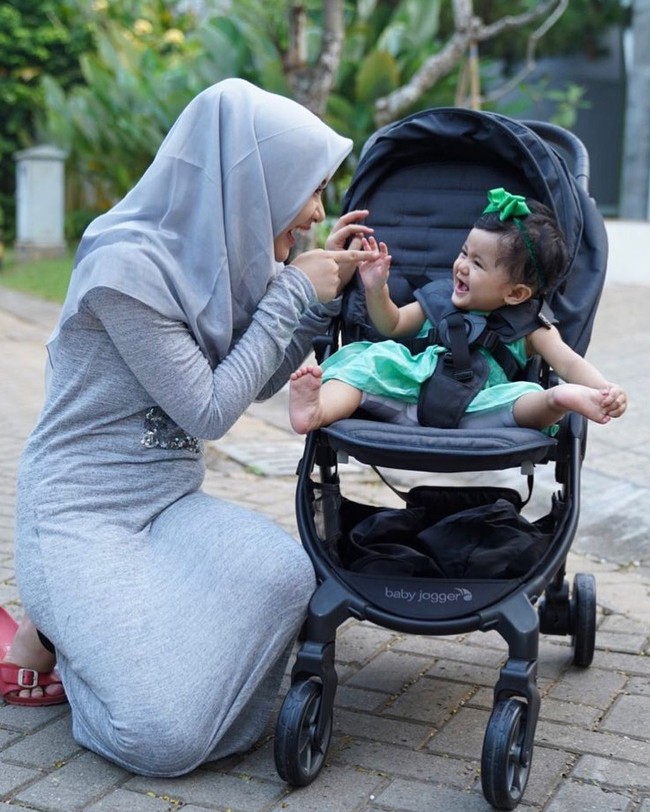 Ryana memilih maxi dress berbahan kaos agar tetap bisa bergerak nyaman tapi tetap sopan saat berjalan-jalan bersama putri kecilnya. Ia pun kerap terlihat memakai hijab segi empat motif yang sedang tren saat ini. Foto: Instagram/Ryana_dea