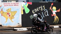 Pengendara motor melintas diantara mural-mural lucu.