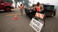 Presiden Donald Trump telah menyatakan kebakaran hutan ini sebagai situasi darurat pada Sabtu (28/7) waktu setempat, dengan memberi izin agar dana federal dikucurkan untuk pemulihan lokasi yang dilanda kebakaran. Foto menunjukkan penutupan ruas jalan menuju area terdampak kebakaran hutan. Foto: REUTERS/Bob Strong