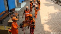 Satpol PP dan PPSU saling bergotong-royong membersihkan gor.