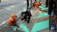 Satpol PP ikut membantu mengecat trotoar.